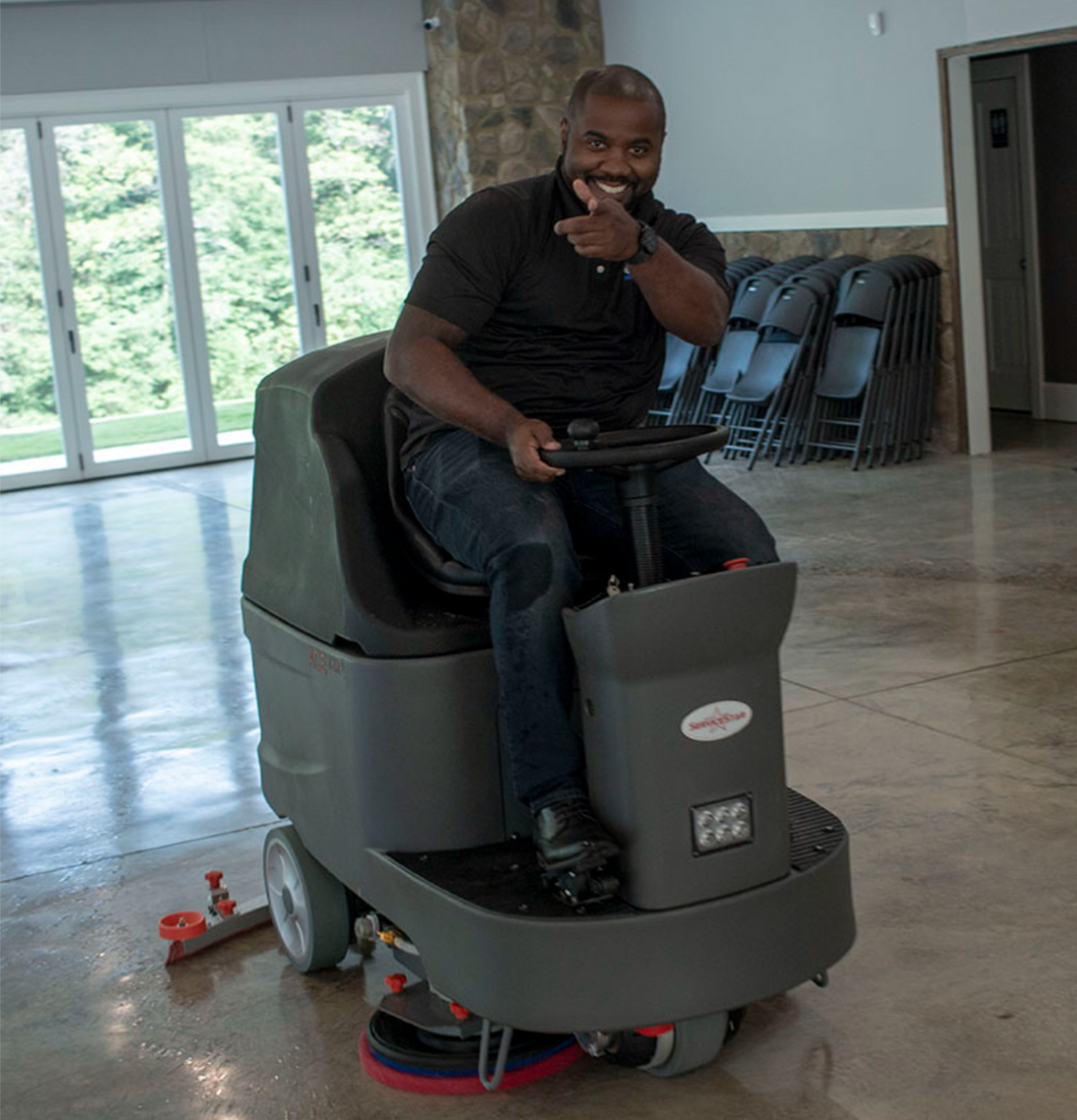 Smiling man rides floor scrubber